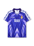 Real Madrid 1996-97 away jersey, front view, purple to blue gradient body with geometric triangle pattern, white sleeve panels with paw print pattern, purple polo-style collar, Kelme logo, Real Madrid crest with crown, white Teka sponsor logo