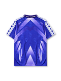 Real Madrid 1996-97 away jersey, front view, purple to blue gradient body with geometric triangle pattern, white sleeve panels with paw print pattern, purple polo-style collar, Kelme logo, Real Madrid crest with crown, white Teka sponsor logo