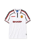 Manchester United 1998-99 away jersey, front view, white body with red and black diamond pattern shoulder trim, zip-up polo collar, red Umbro logo, Manchester United crest, red Sharp sponsor logo