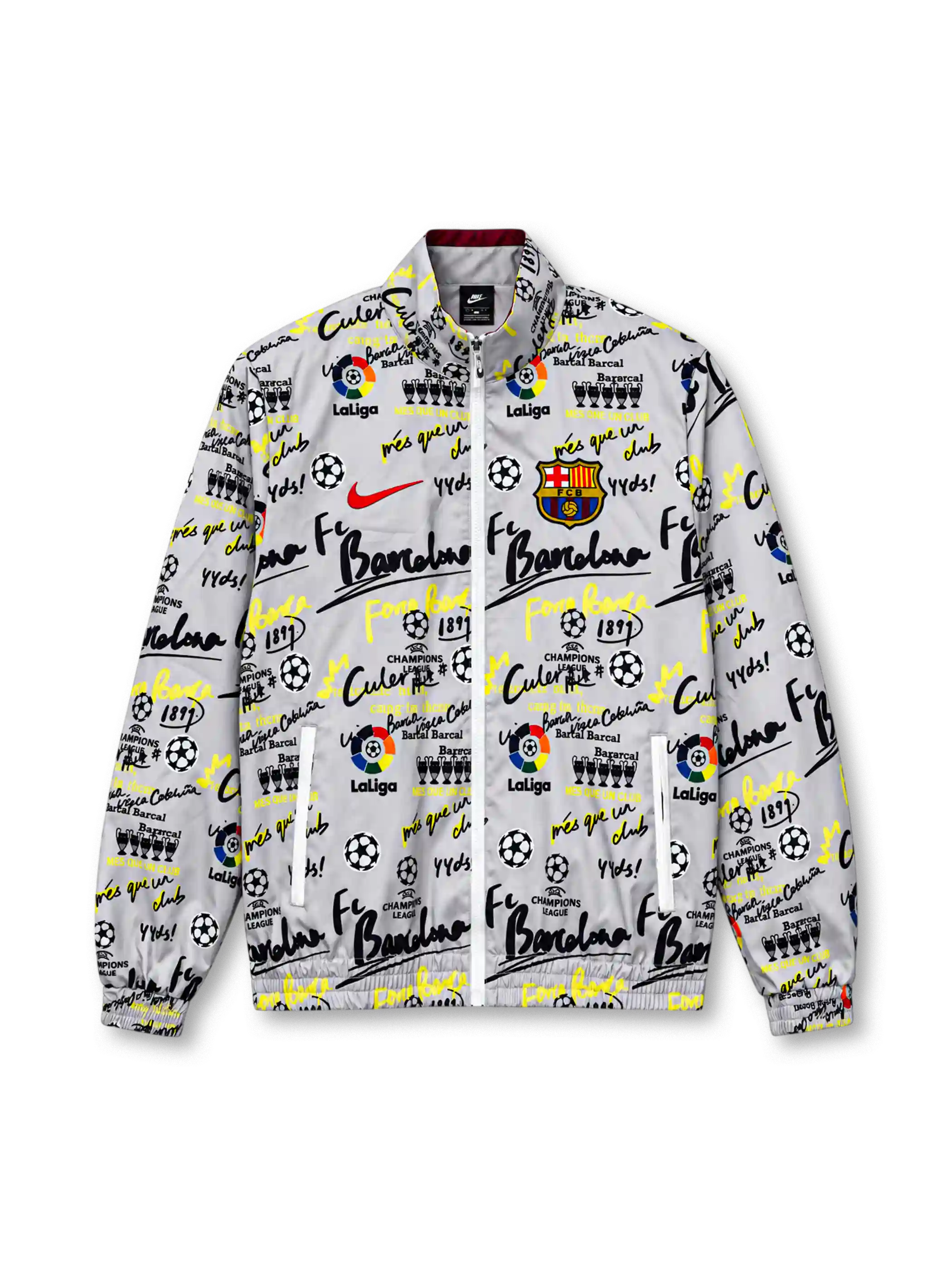 Front view of a white FC Barcelona-inspired graffiti track jacket featuring black and neon yellow lettering, soccer ball and trophy graphics, LaLiga-inspired motifs, a red Nike Swoosh, colorful Barcelona crest, full zipper, and elasticated cuffs.