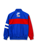 Front view of a Paris Saint-Germain 1996/97-inspired track jacket featuring a royal blue body, red horizontal chest band, red left sleeve, white stripes on the opposite sleeve, white Nike Swoosh, Opel lettering, Paris-themed crest, full zipper, and ribbed cuffs.