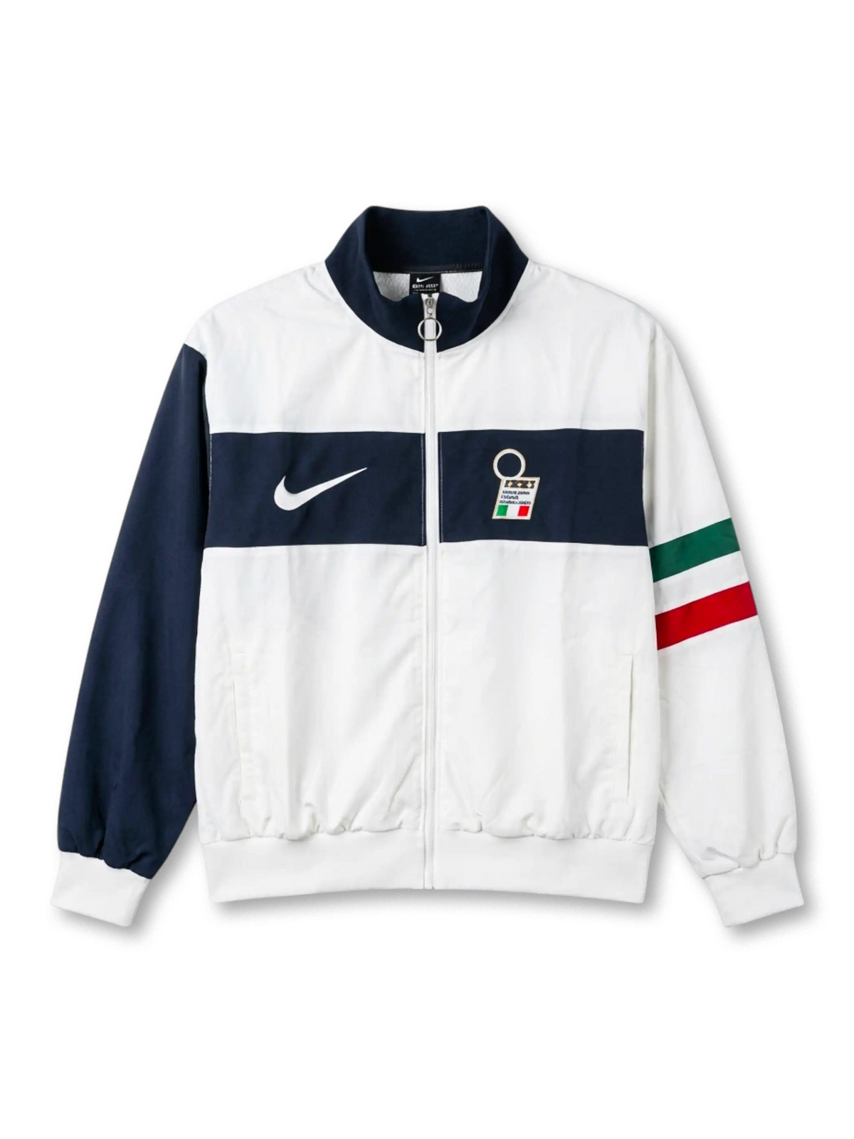 Italy national team Nike track jacket in white with wide navy horizontal chest band, navy stand collar, navy left sleeve, Italian tricolor flag stripe on right sleeve, white Swoosh at left chest, FIGC crest badge at right
